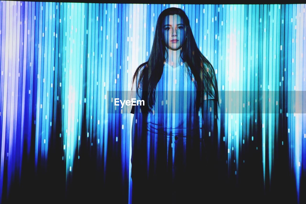 Digital composite image of woman and illuminated blue lights