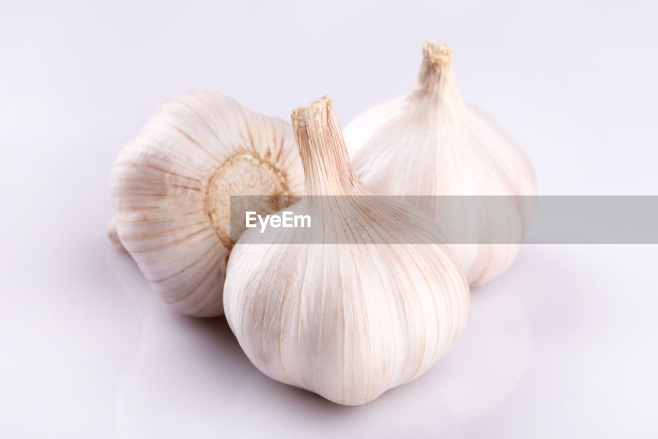 CLOSE-UP OF GARLIC ON WHITE SURFACE