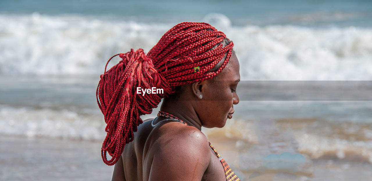 African woman with tied red rasta braided hair on a beach in ghana west africa