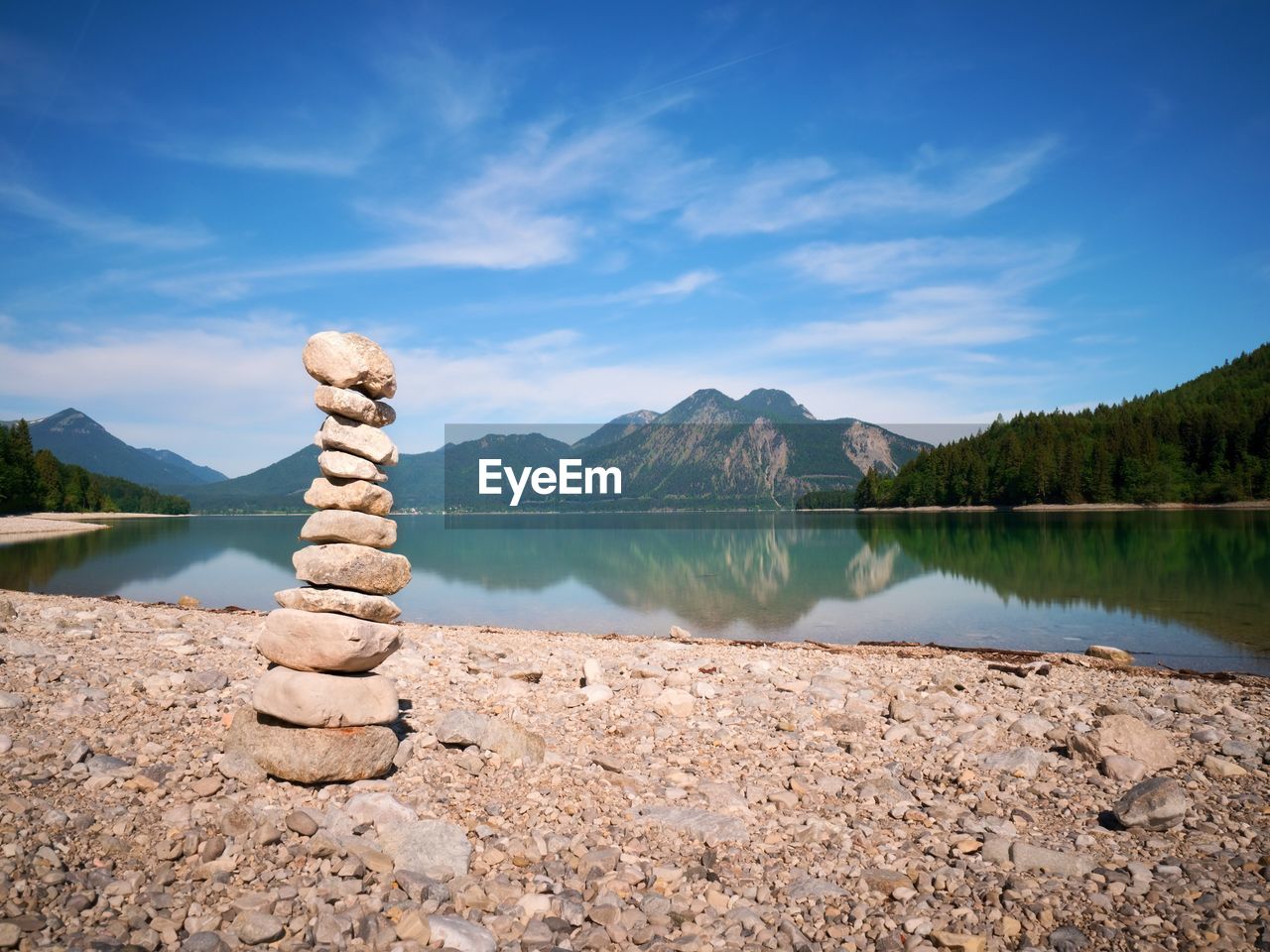 Stacked pebbles on the lake shore. balanced stones stack at water with reflection
