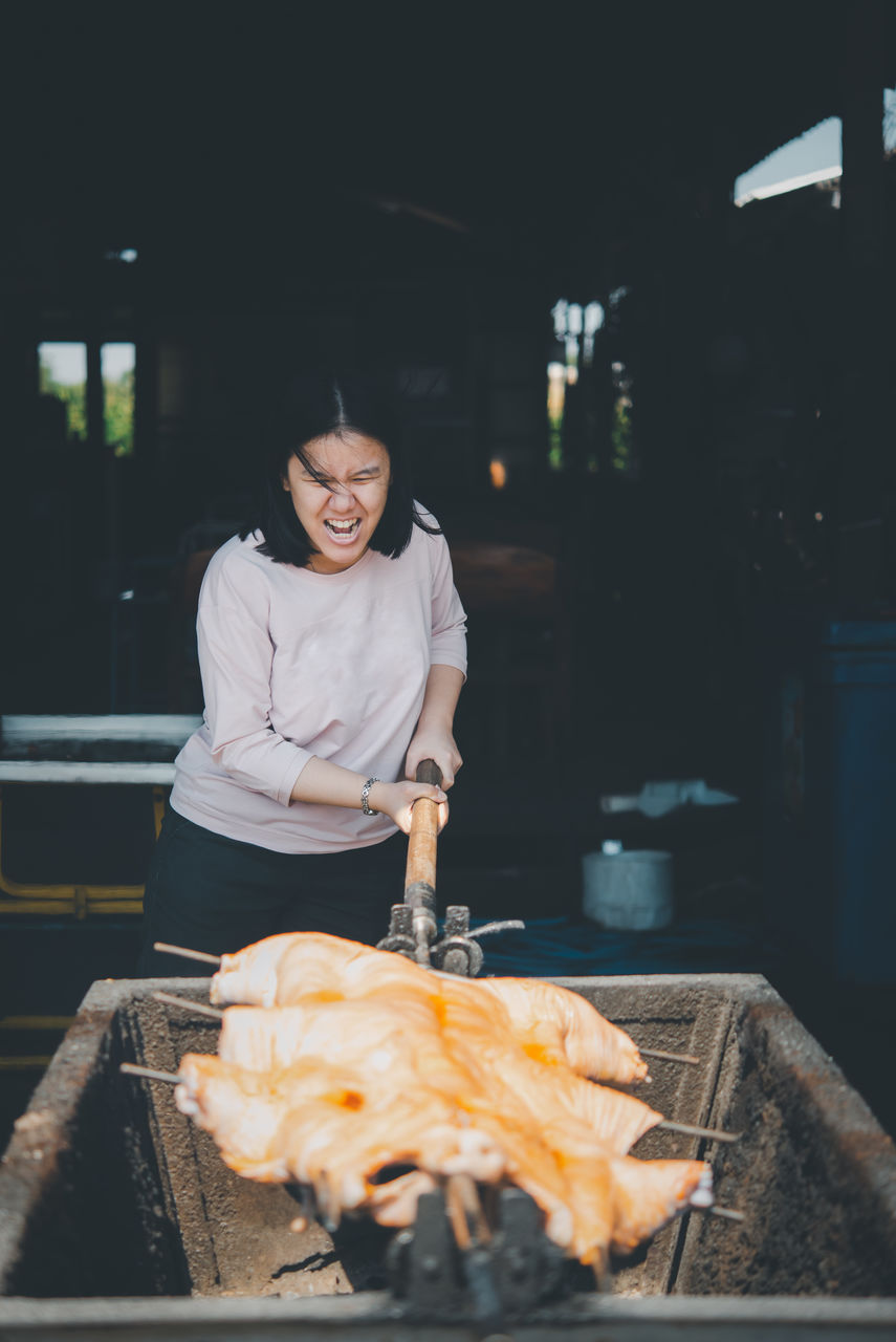 Young woman cooking meat on barbeque