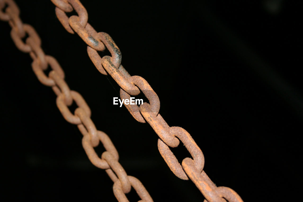 Close-up of rusted chain against black background