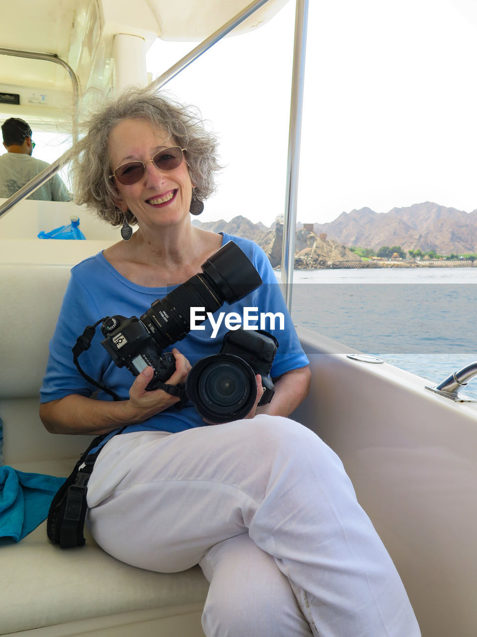 Portrait of smiling senior woman holding digital camera while sitting in boat