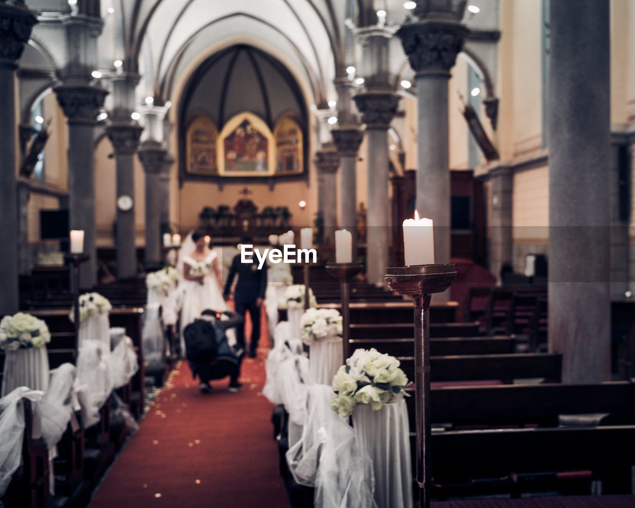 Rear view of man photographing newlywed couple in church