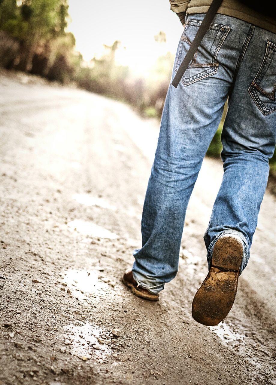 Low section of man walking on wet road