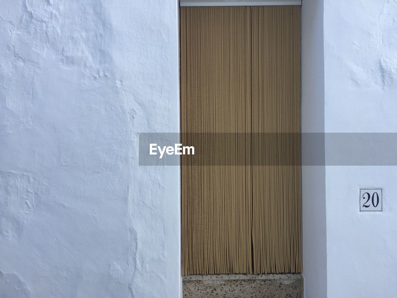 Beaded curtain on doorway of white house with number