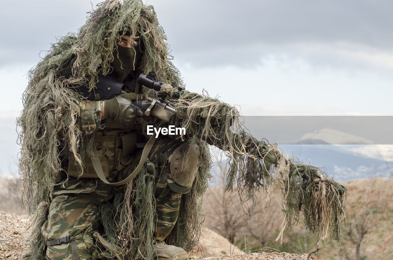 Army Man In Ghillie Suit With Rifle On Field On Eyeem