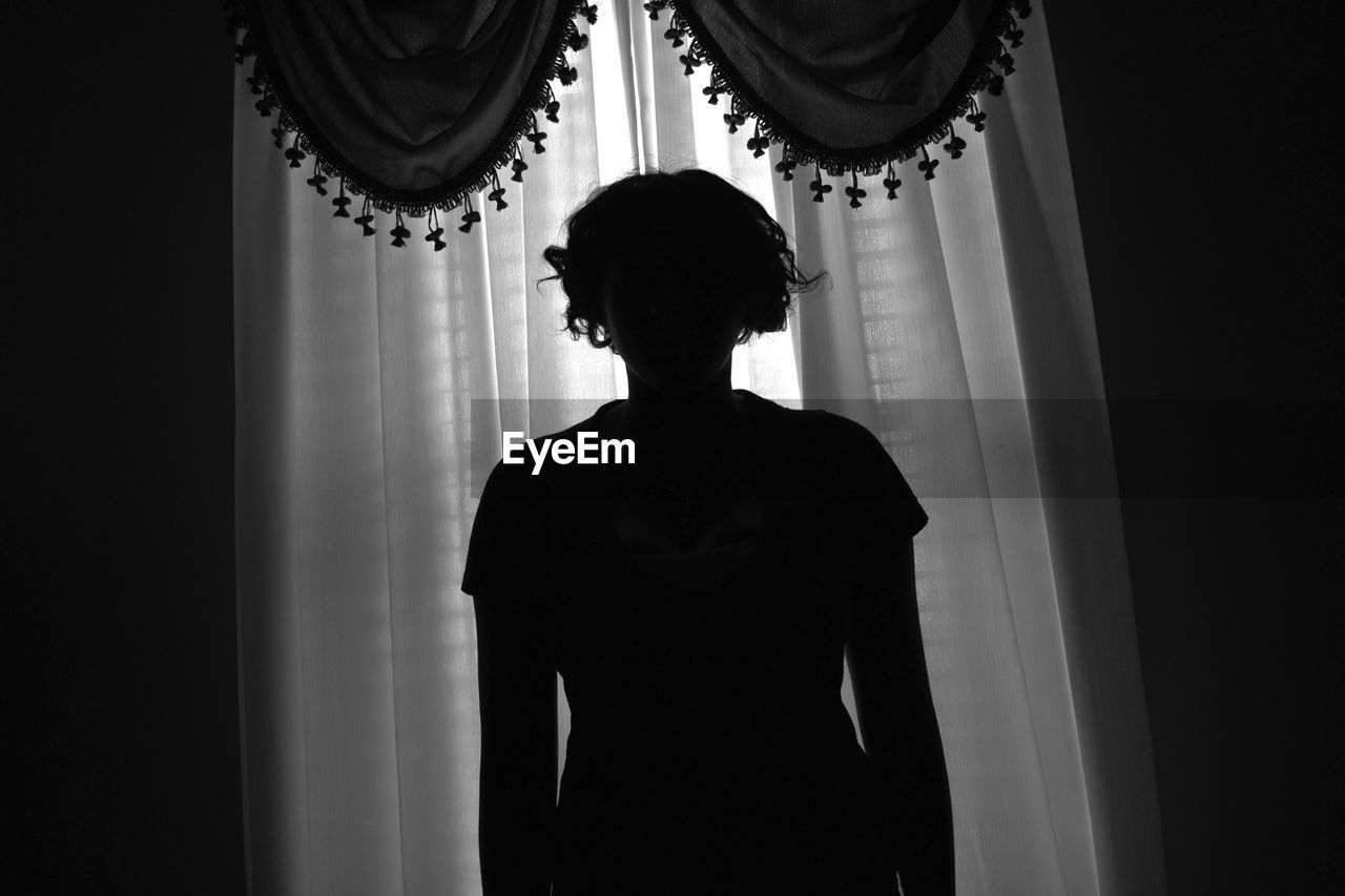 REAR VIEW OF A SILHOUETTE WOMAN STANDING IN CORRIDOR