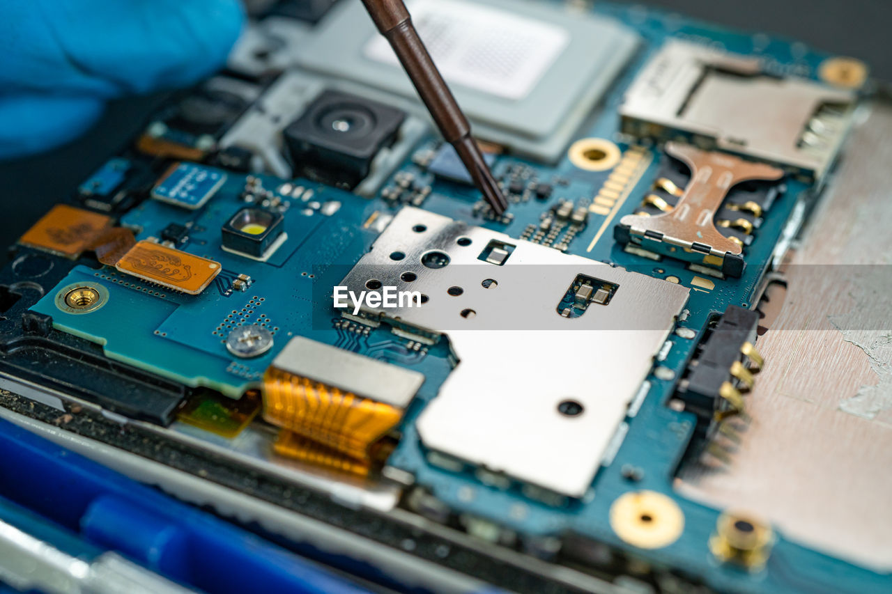 Technician repairing inside of mobile phone by soldering iron. integrated circuit.  