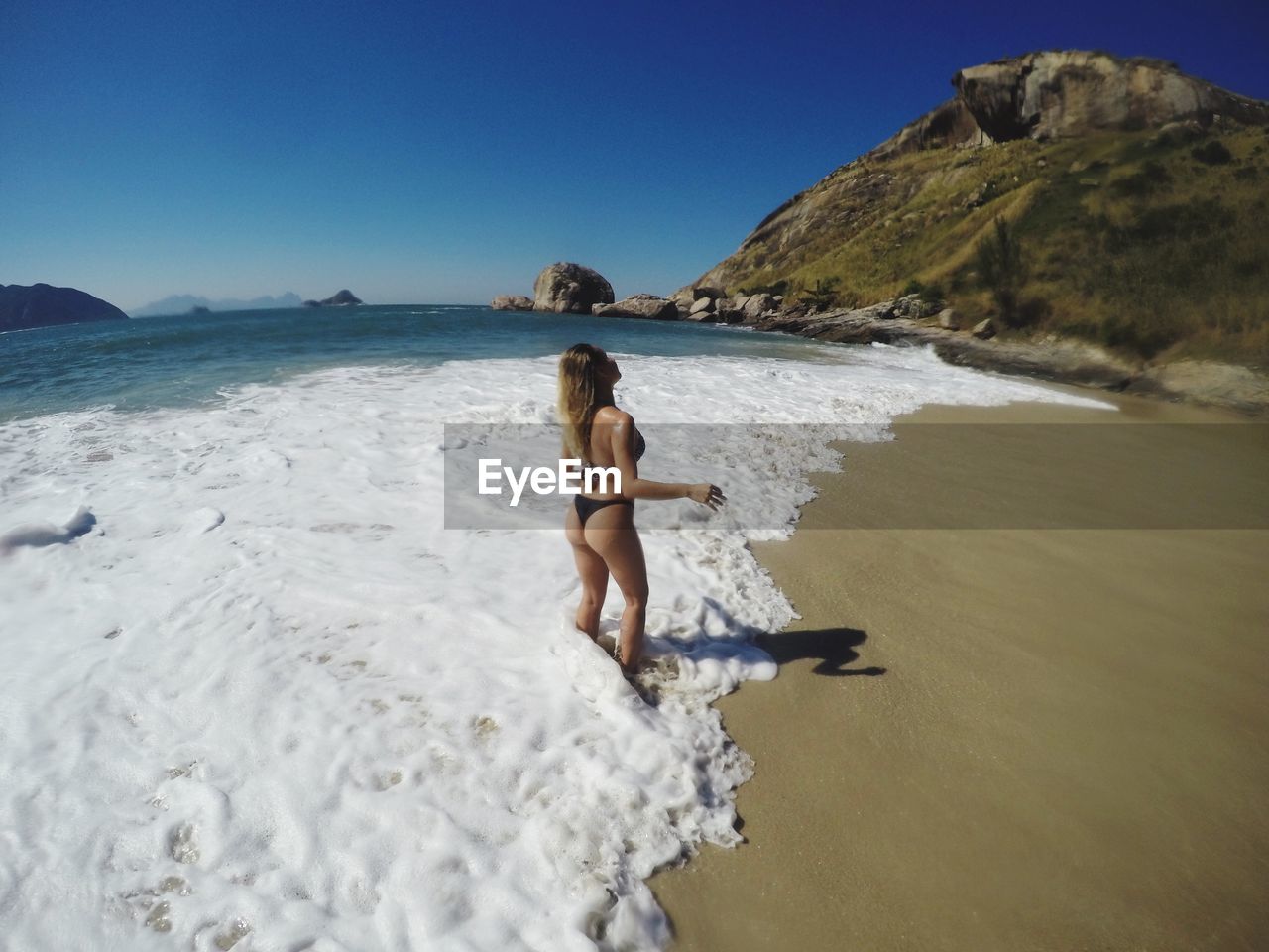 Seductive woman wearing bikini while standing on shore at beach