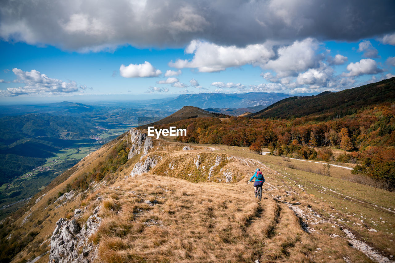 Woman mountain biking on footpath near ridge on mount nanos above vipava, slovenia.