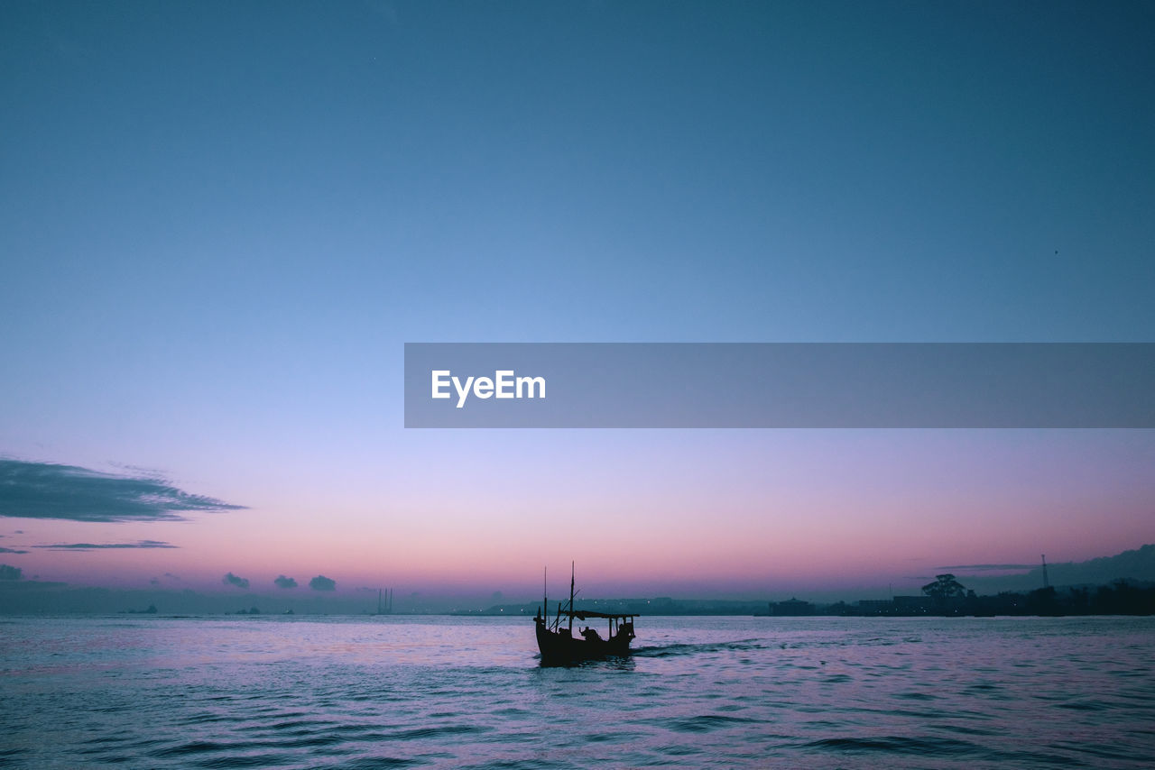 BOAT IN SEA AGAINST CLEAR SKY DURING SUNSET