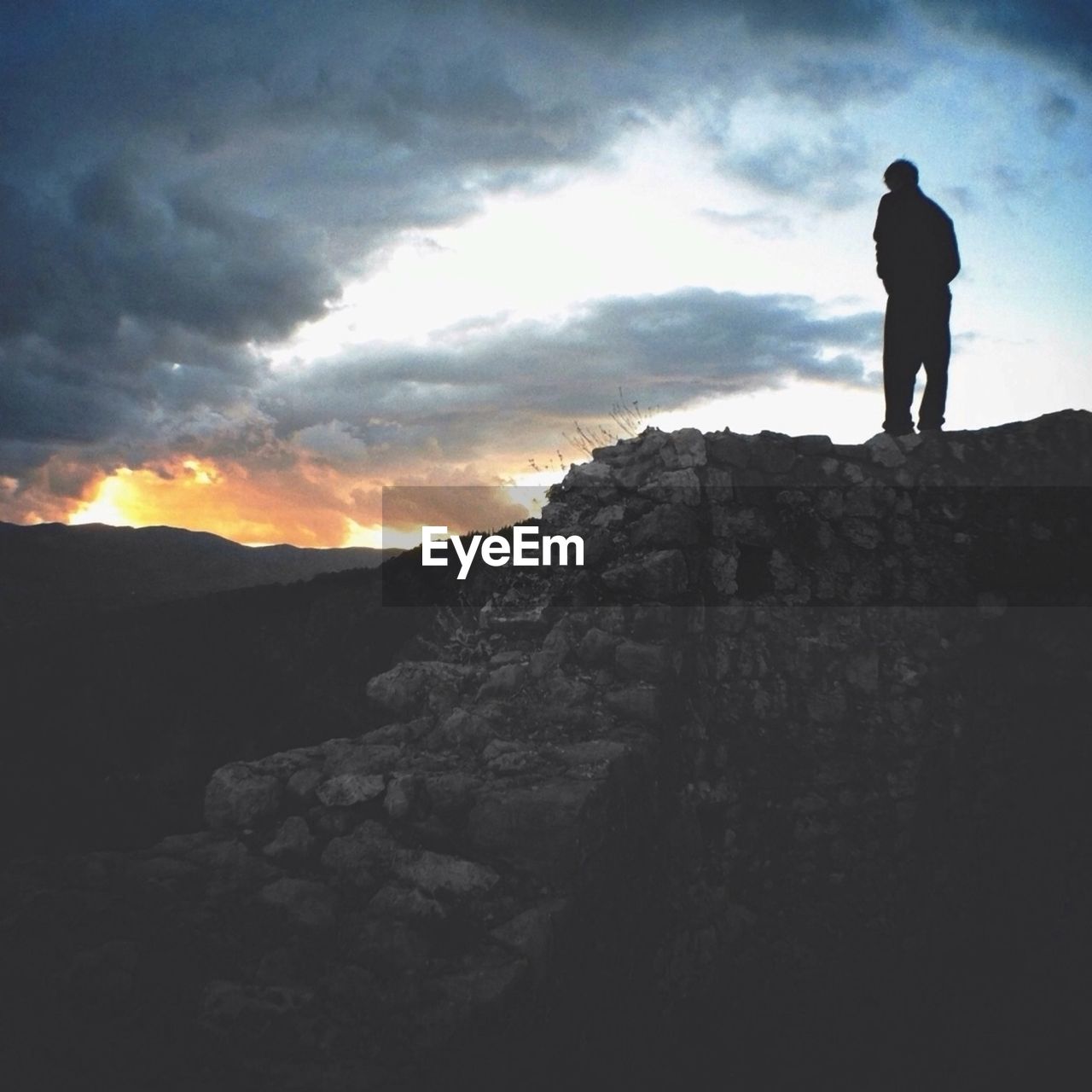 Low angle view of silhouette man standing against scenic sky