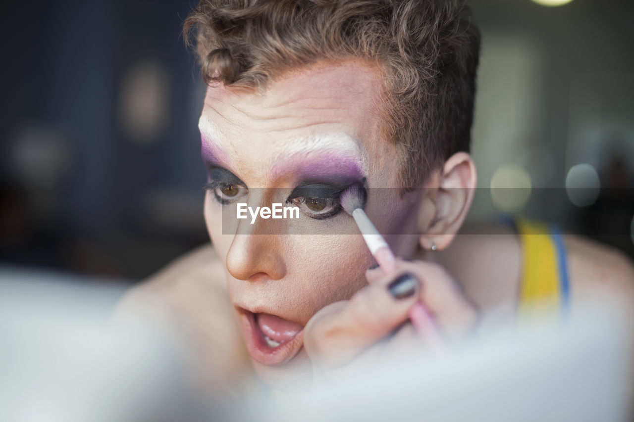 Young man applying drag queen makeup