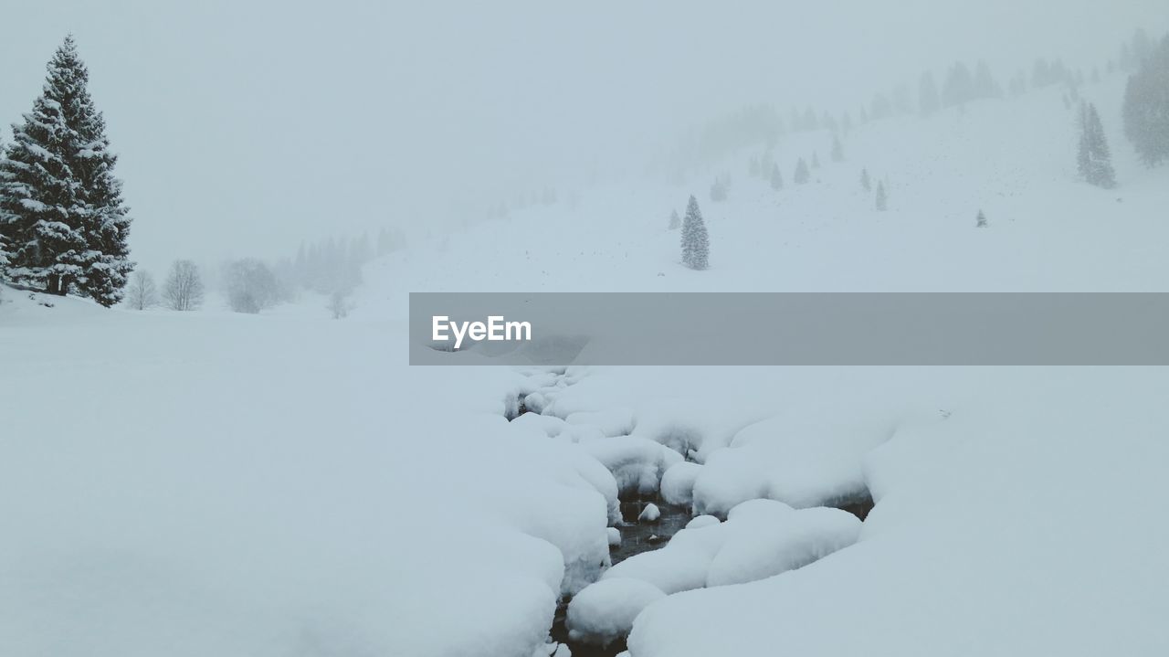 Scenic view of snow covered field in foggy weather