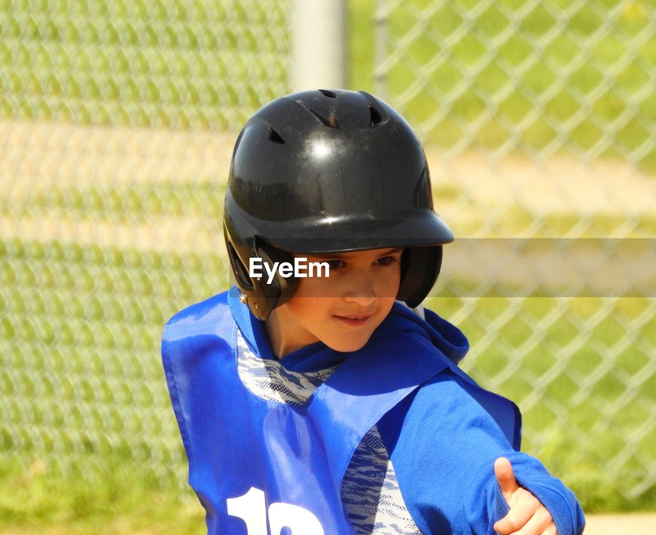 Portrait of boy wearing helmet while gesturing on field
