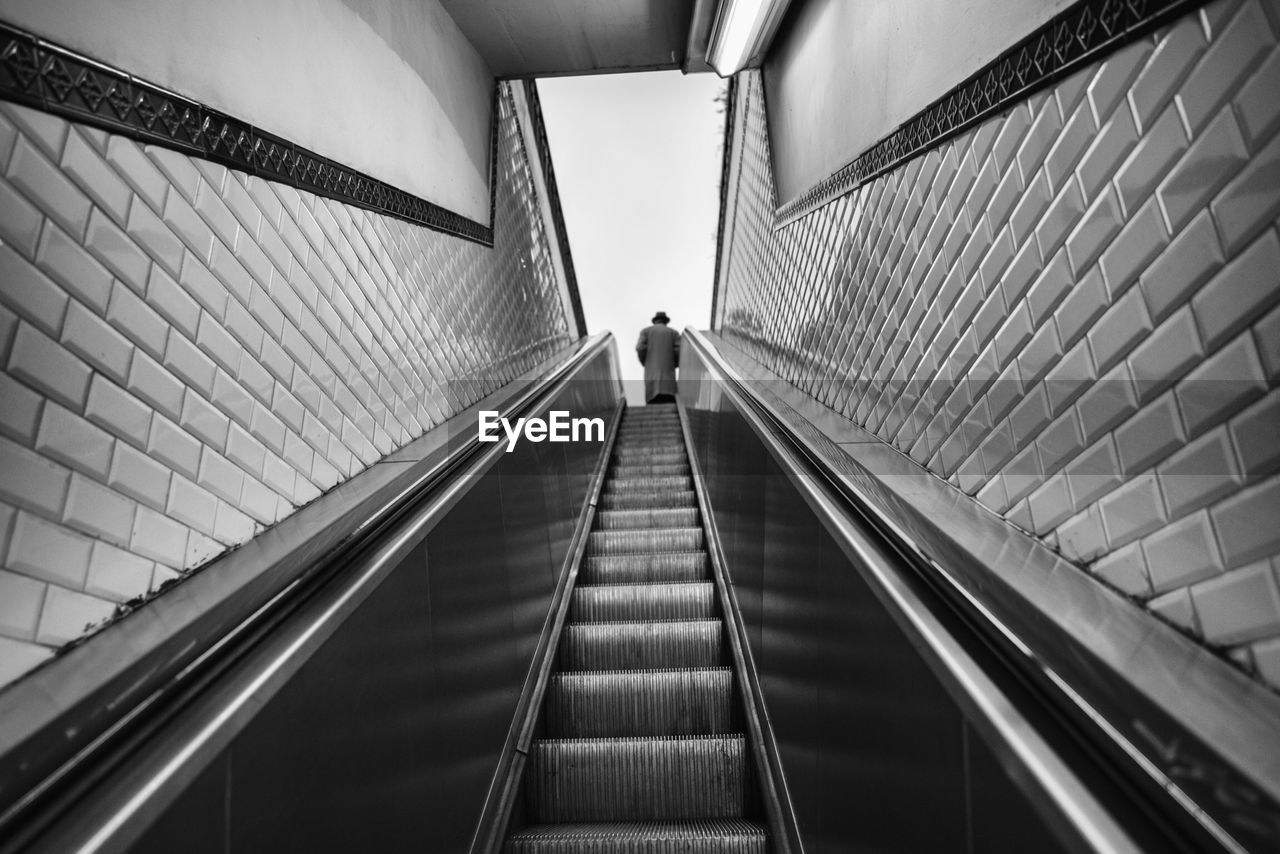 Low angle view of man standing on escalator