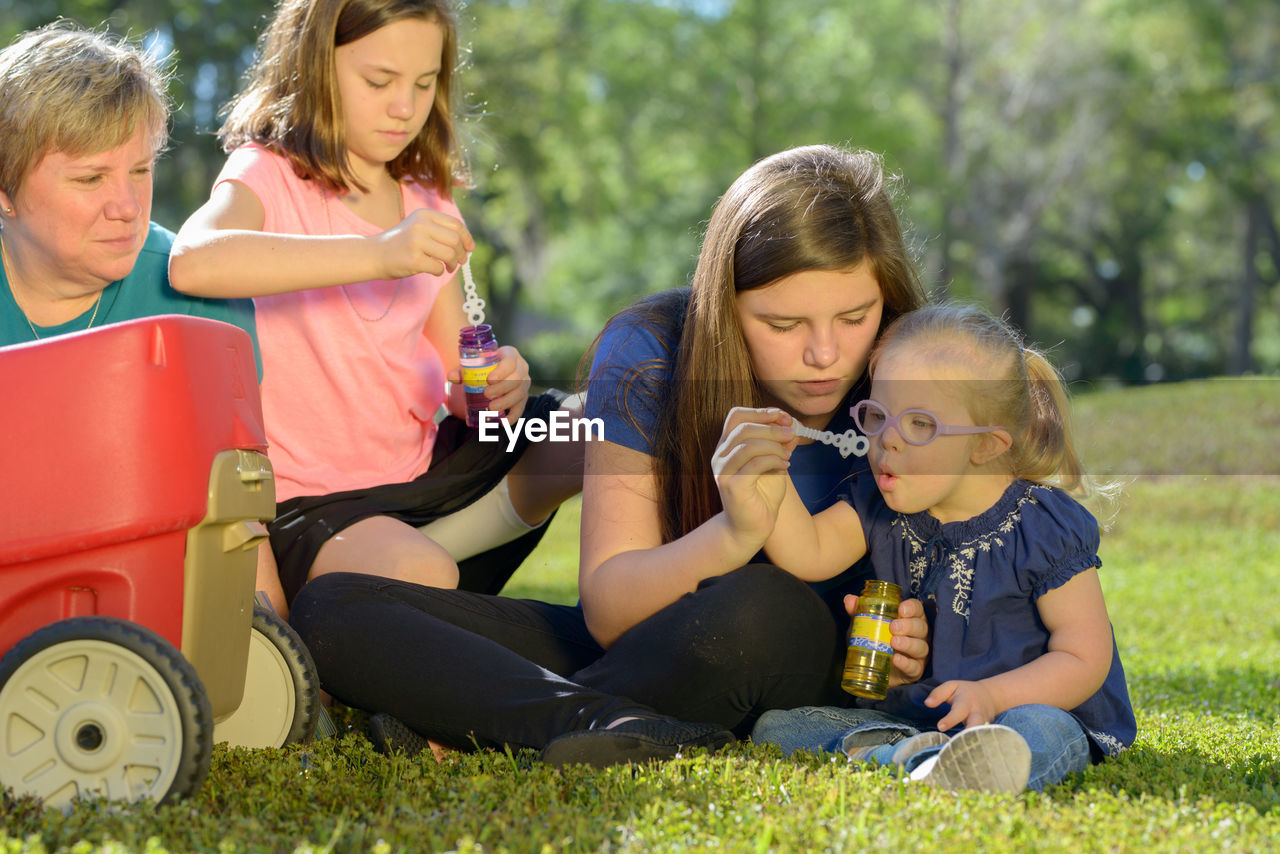 Daughters with mother sitting on field