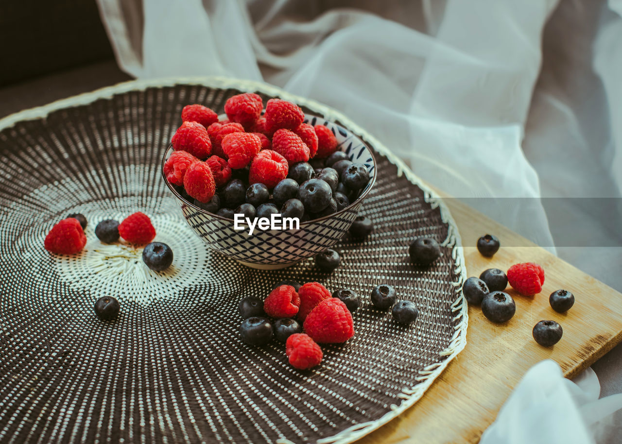 Little bowl with raspberries and blueberries, in a nice background.