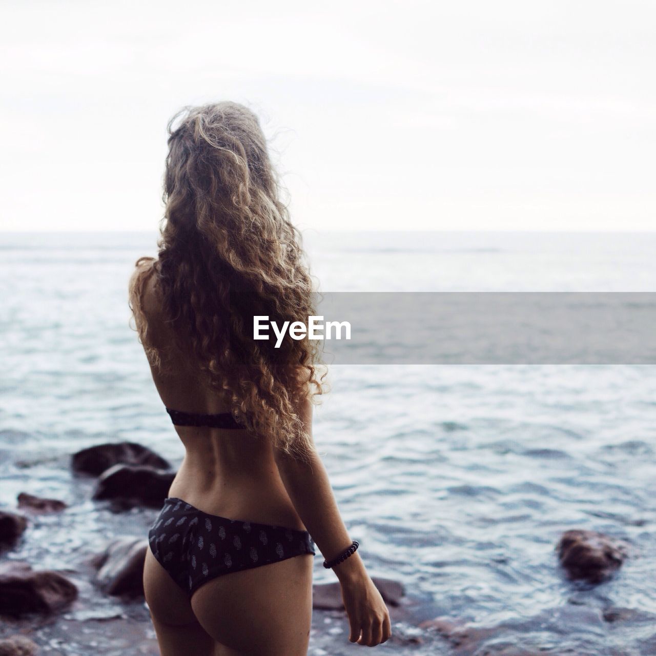 Rear view of woman in bikini overlooking sea