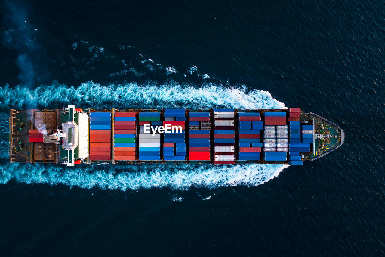 Aerial top view full speed container ship in the deep blue sea for cargo logistics import and export 