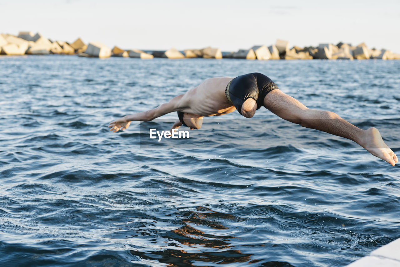 Disabled man diving into water on sunny day