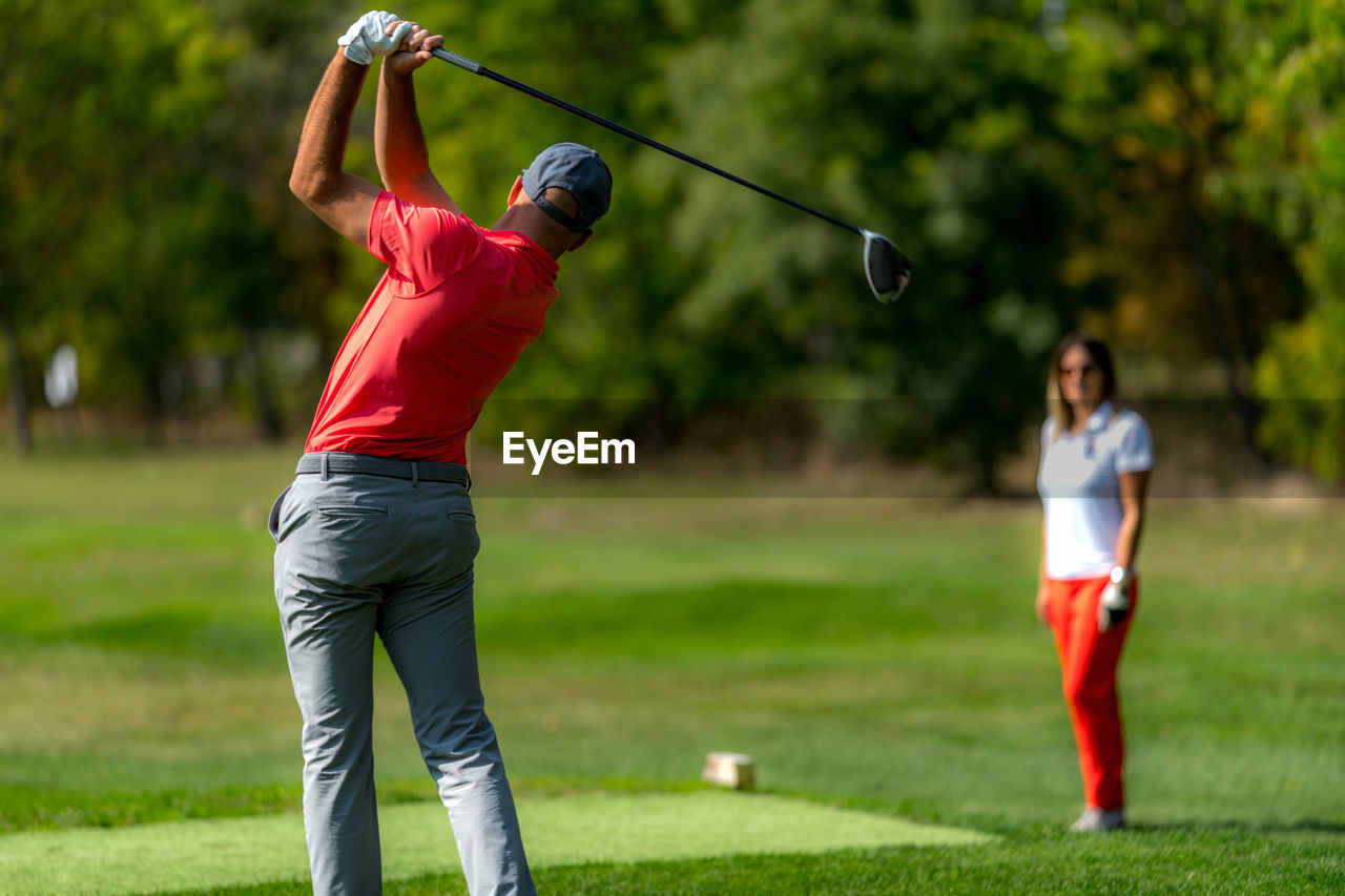 Young couple on a golfing vacation, man teeing off