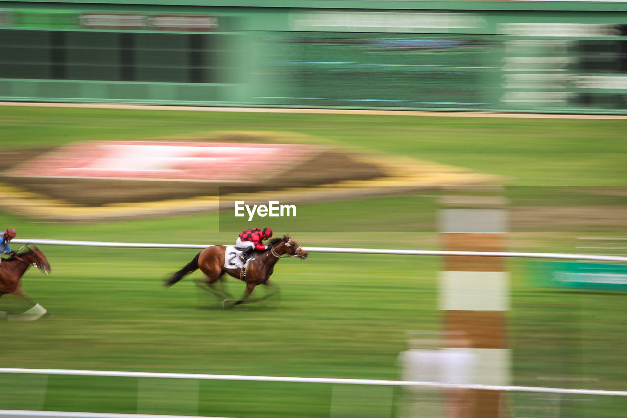 Blurred motion of jockeys riding horses in race