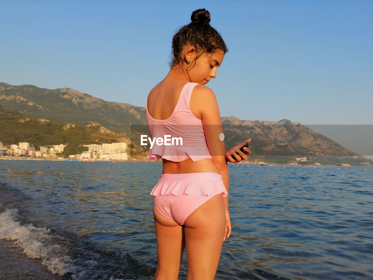 Life with diabetes. girl checks glucose level before enters the sea with cgm device