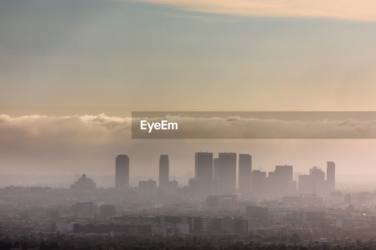 Modern cityscape against sky during sunset