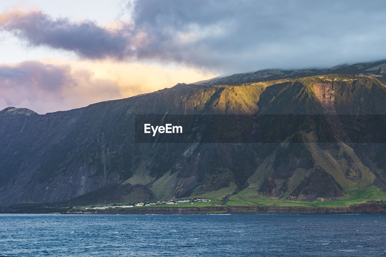 Scenic view of sea by mountains against sky