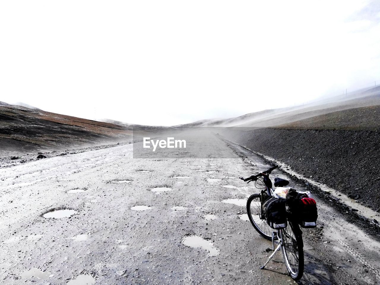View bicycle with packs on road against clear sky