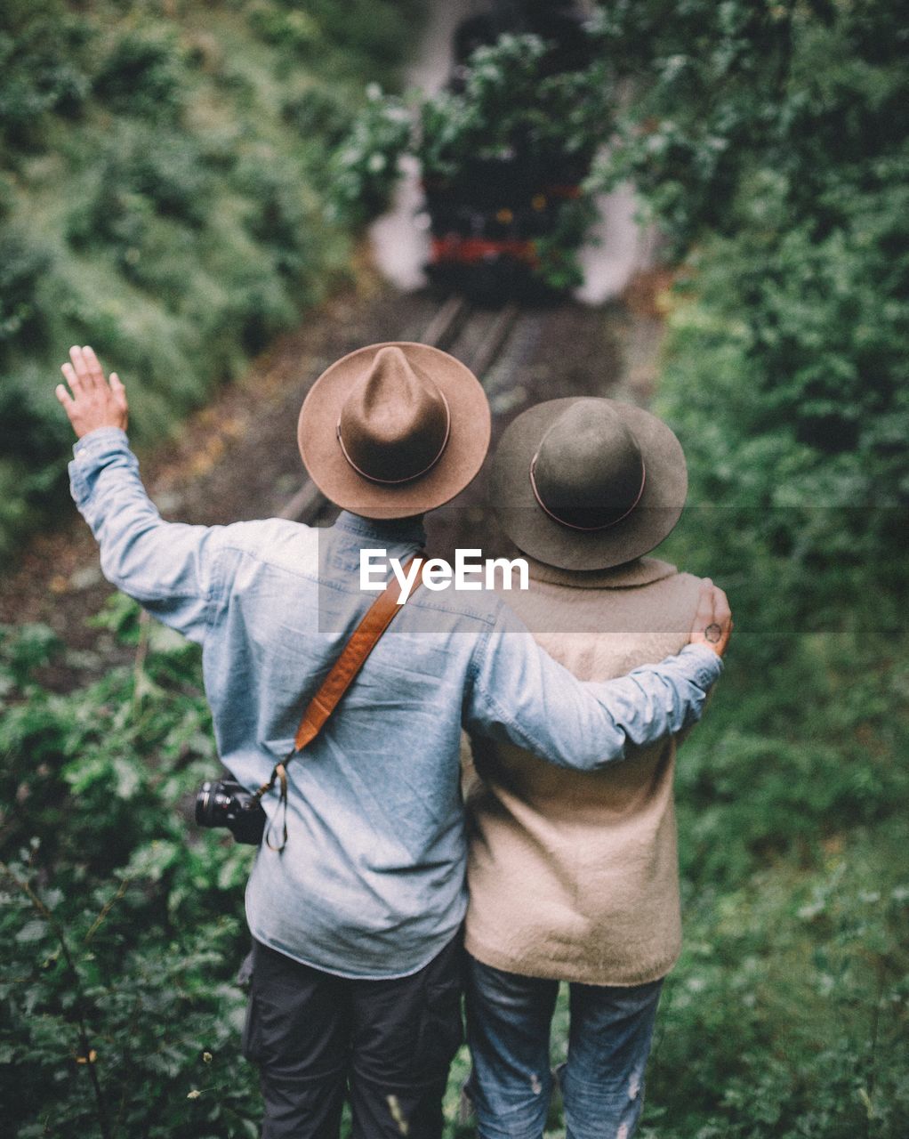 Rearview of couple looking at train in forest 