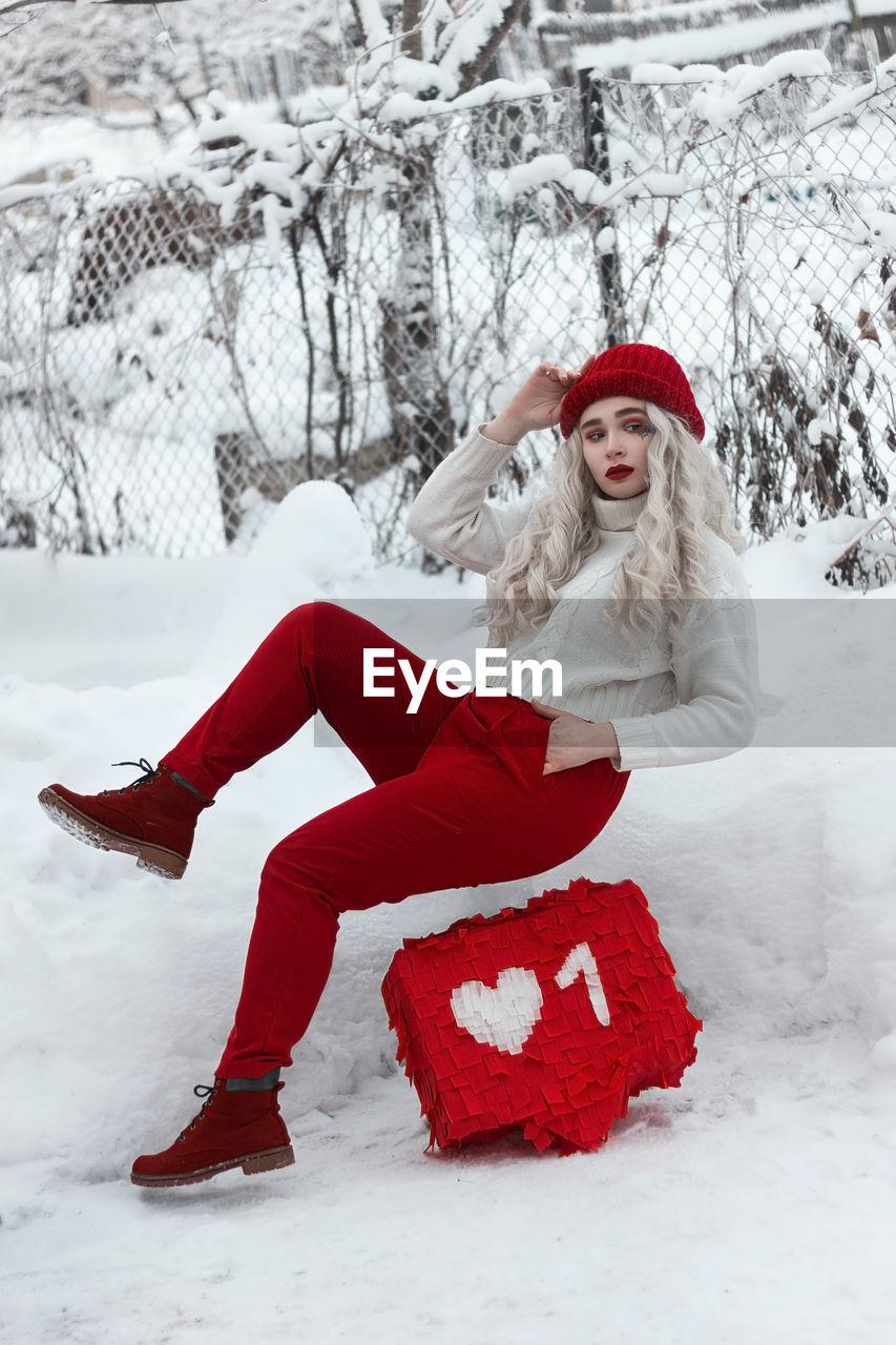 Portrait of young woman sitting on snow covered field