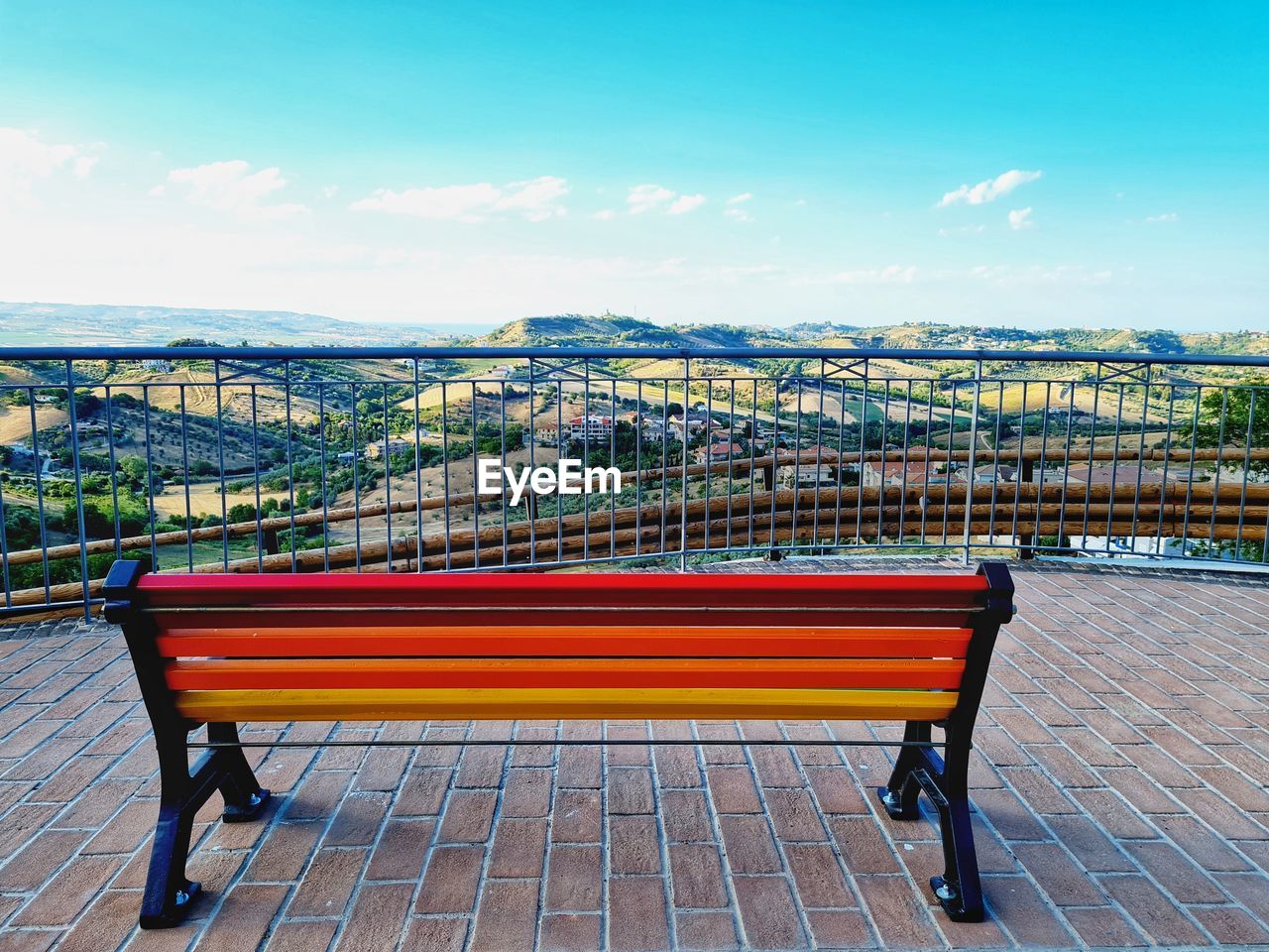 EMPTY BENCH AGAINST CITYSCAPE