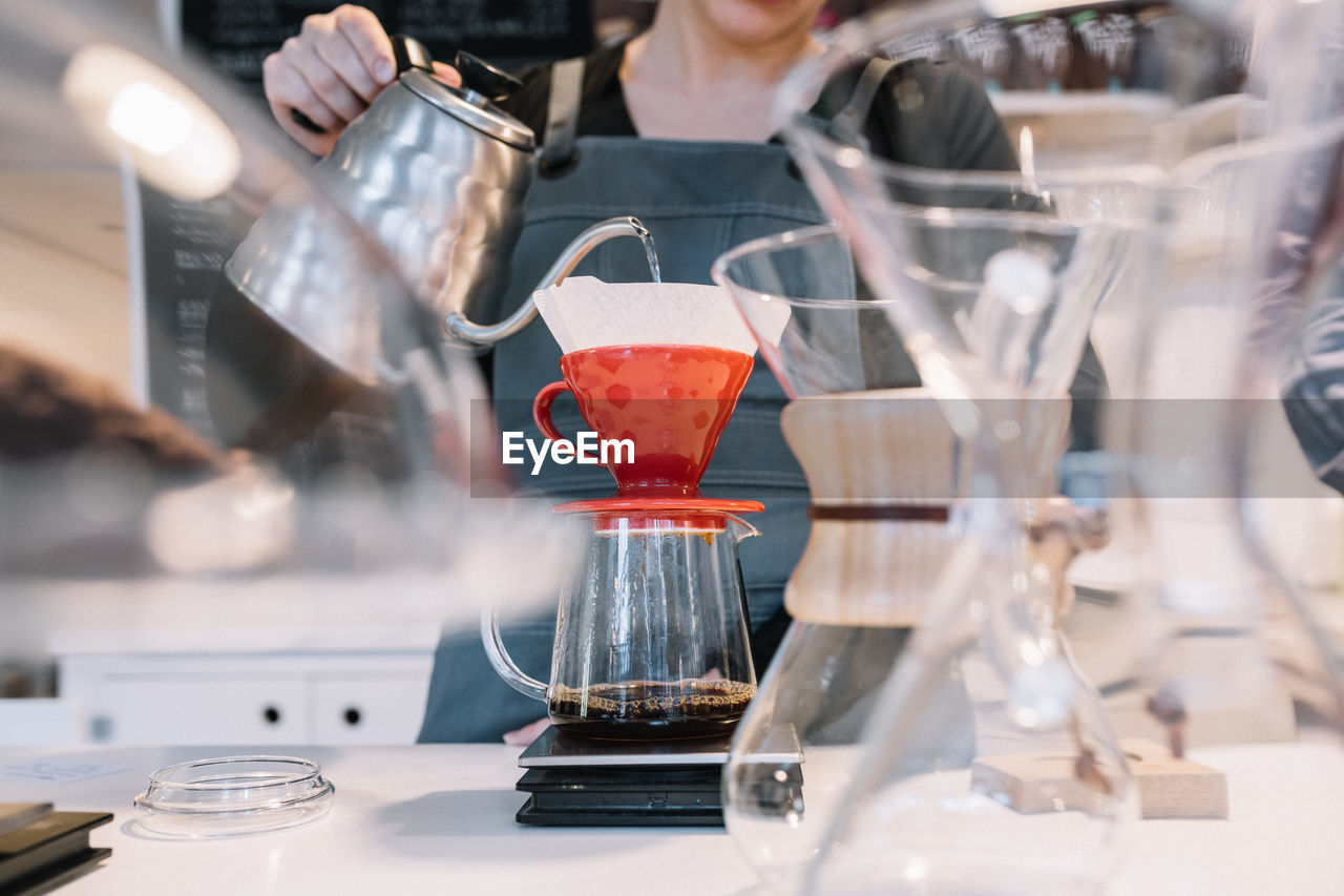 MIDSECTION OF PERSON POURING COFFEE IN KITCHEN