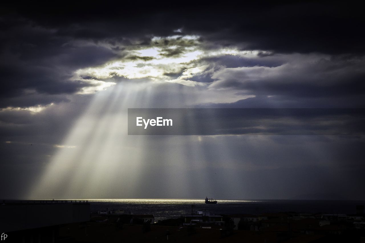 Sunlight streaming through storm clouds over sea