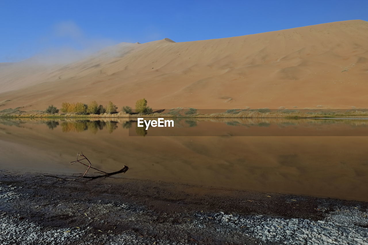 SCENIC VIEW OF ARID LANDSCAPE AND LAKE AGAINST SKY