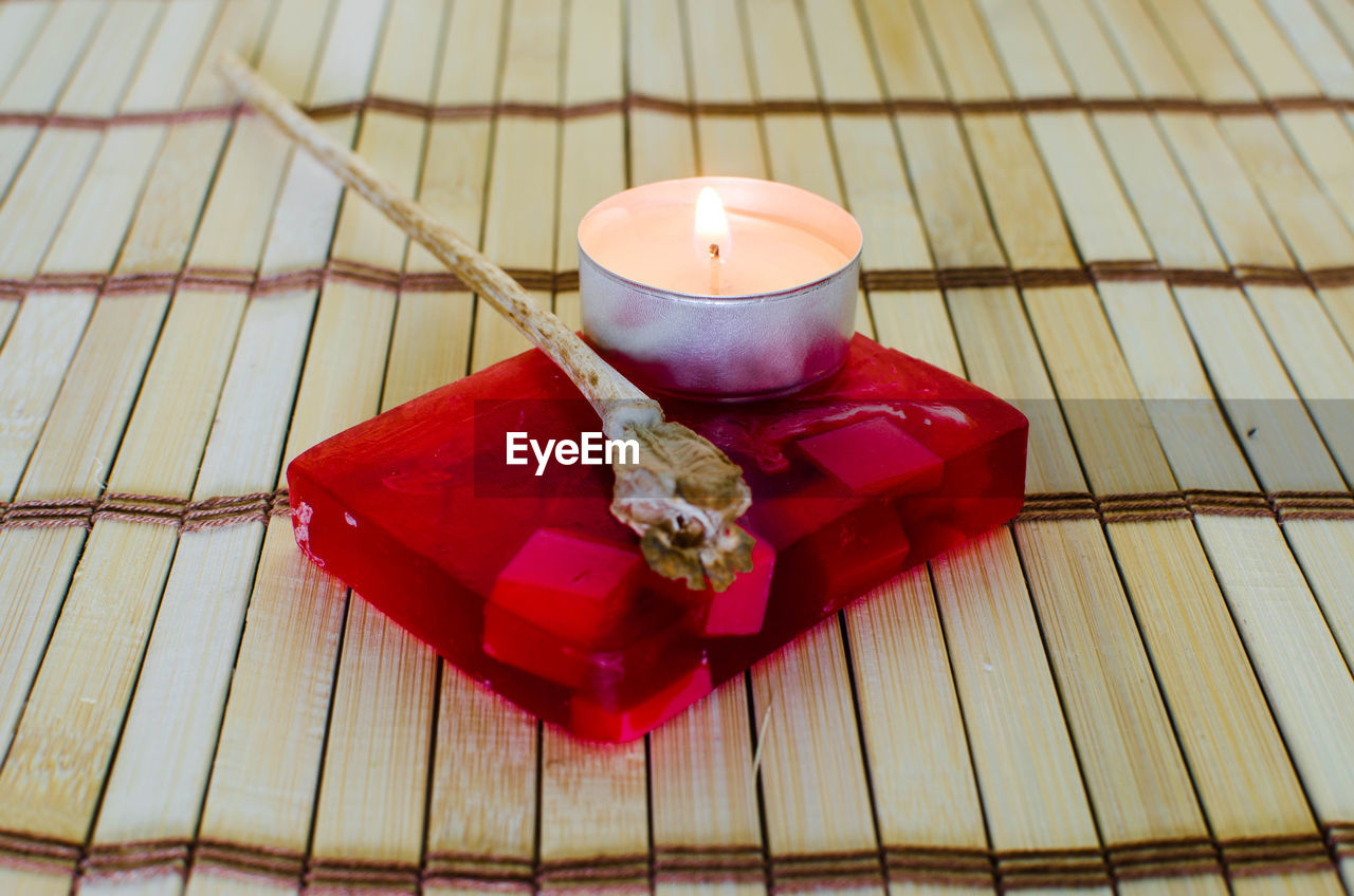 HIGH ANGLE VIEW OF RED AND CANDLES ON WOODEN TABLE