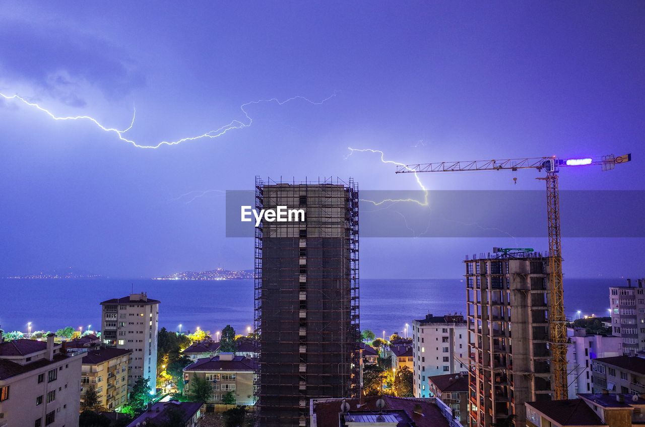 Lightning above sea and buildings in city