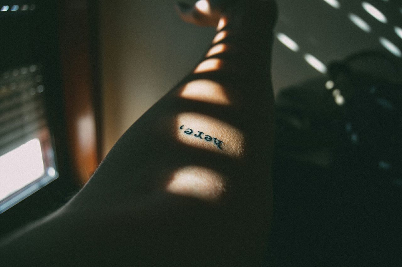 Cropped hand of person with tattoo at home