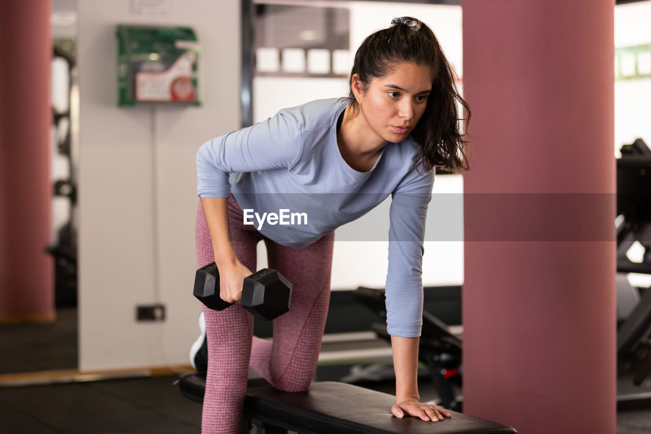 side view of young woman exercising in gym