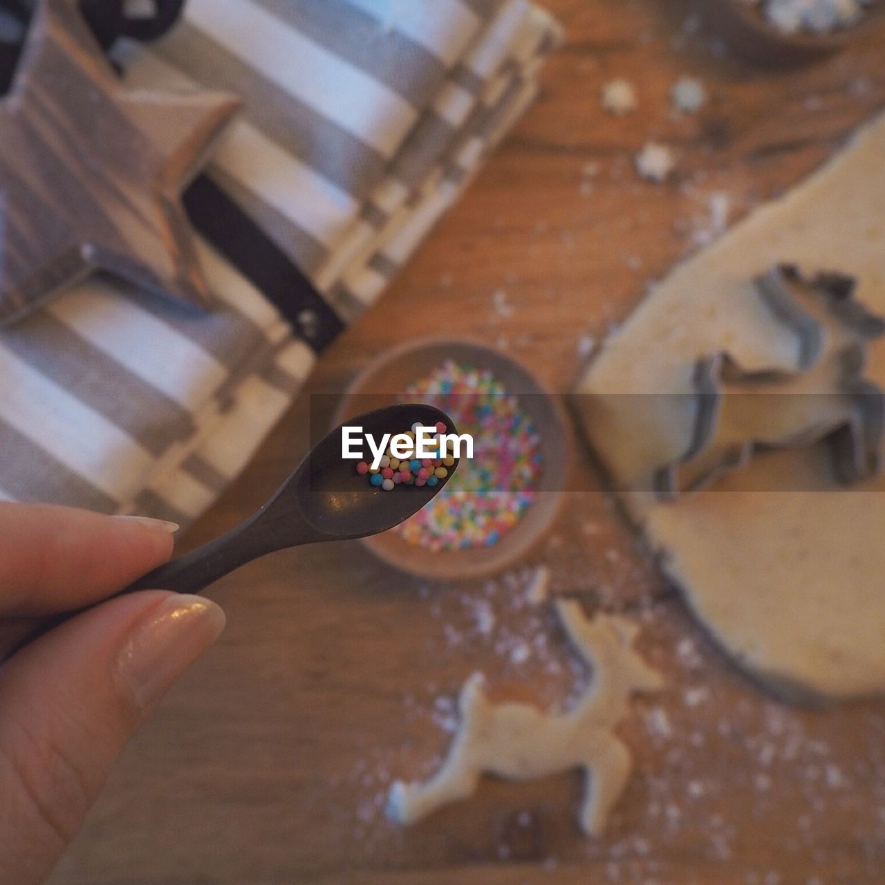 Cropped image of person holding sprinkles in spoon