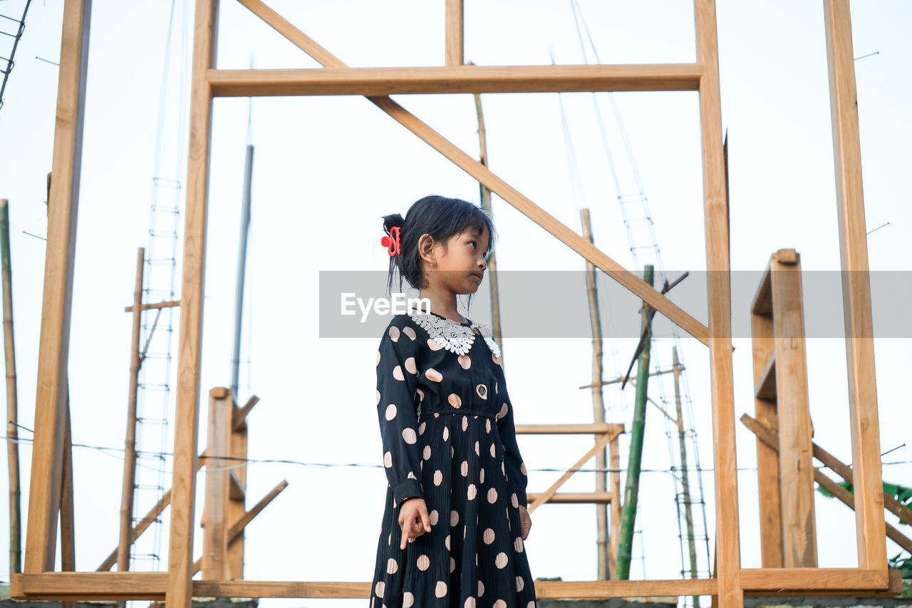 A little asian girl is angry in front of a house building