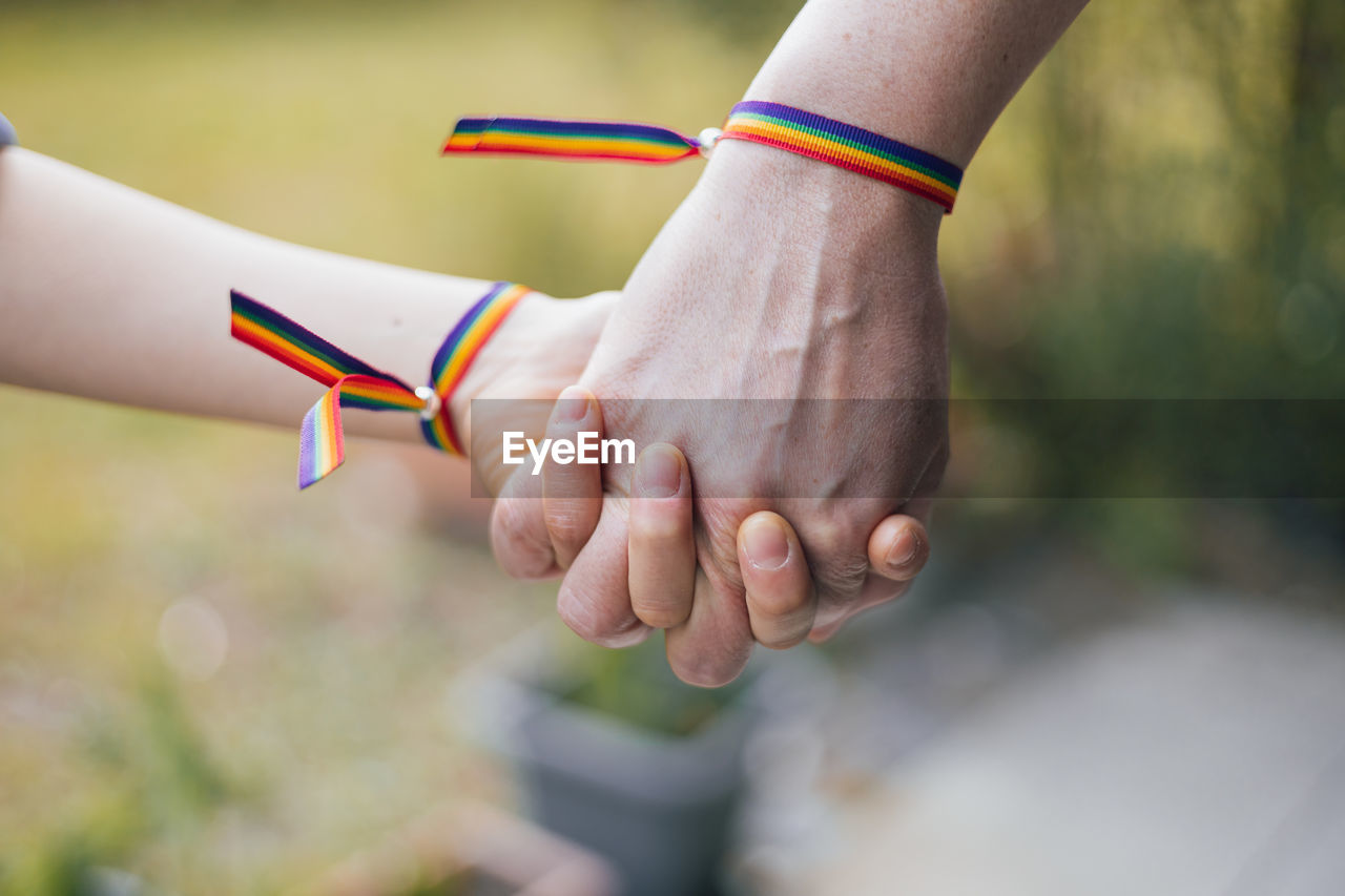 Mother and daughter holding hands with a rainbow-bracelet