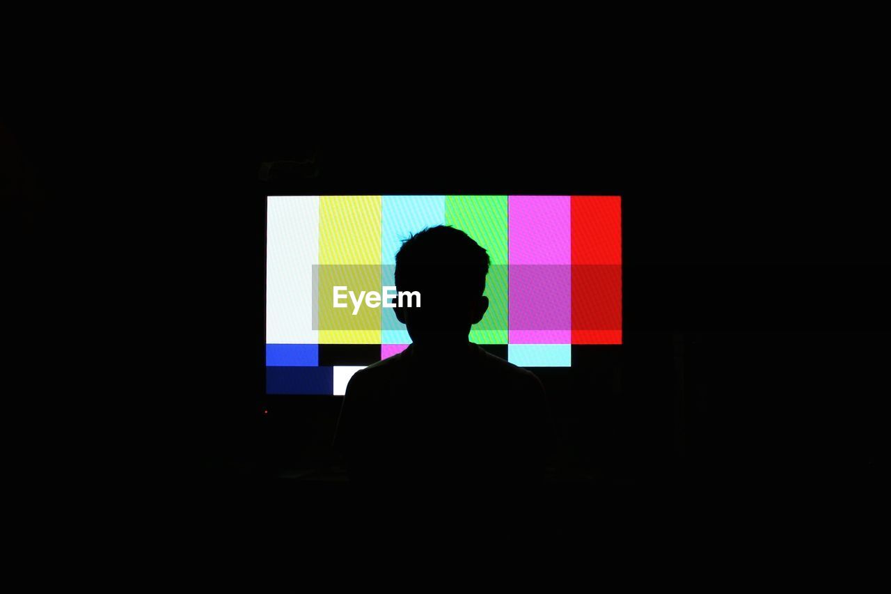 Silhouette of boy in front of television screen