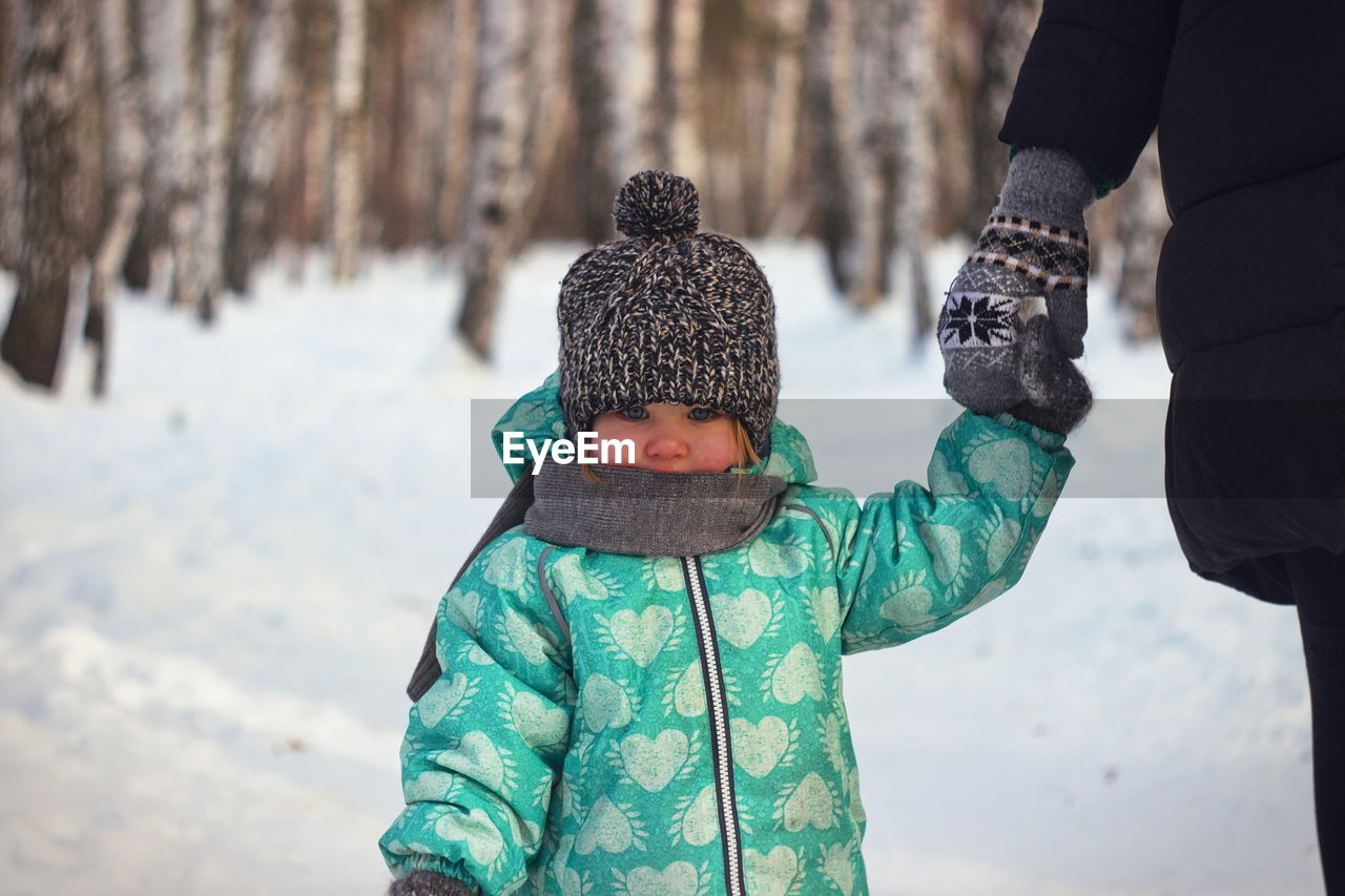 Cropped hand of person holding baby during winter