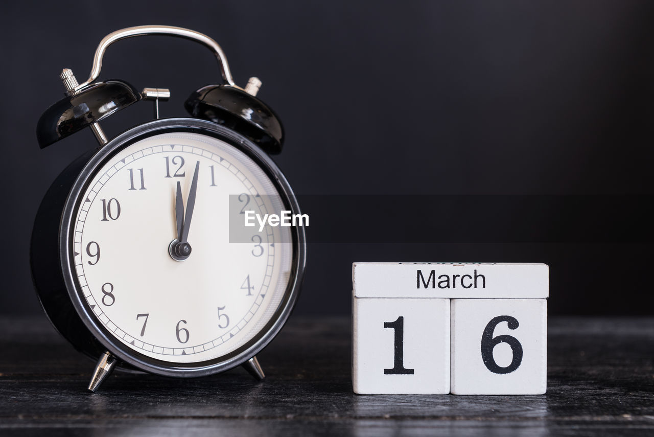 Close-up of alarm clock with calendar on table