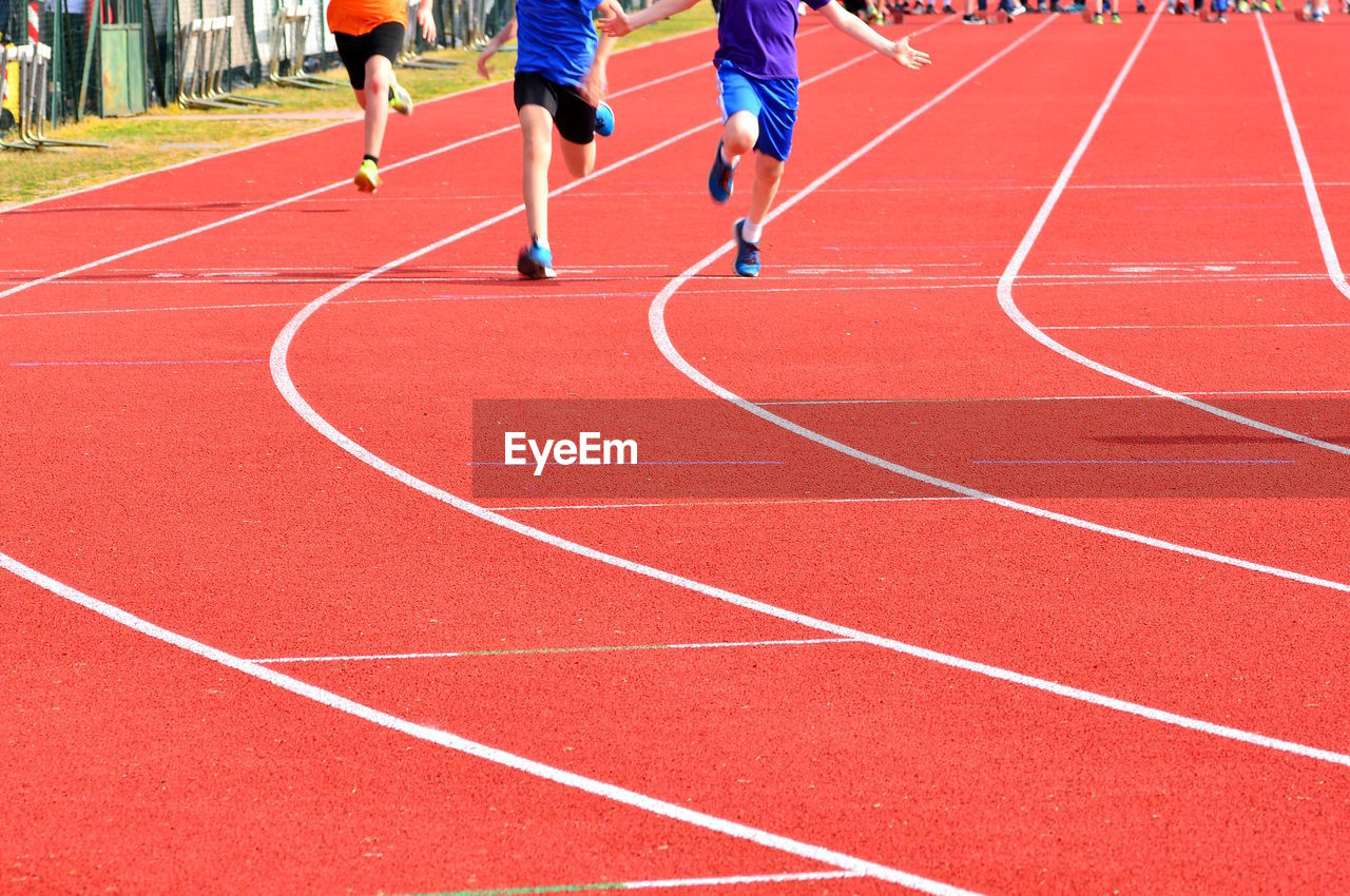 Rear view of athletes running on sports track