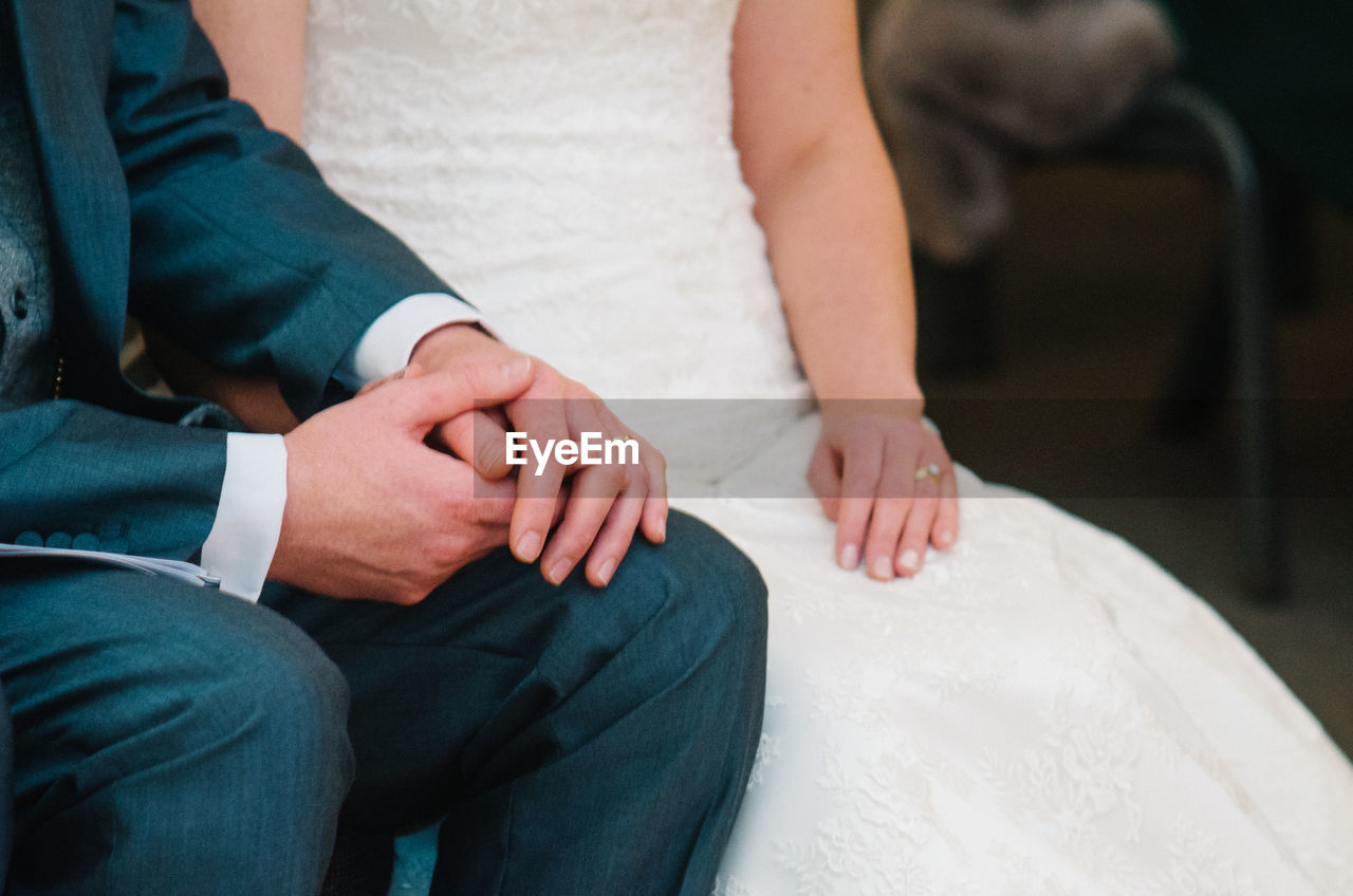 Midsection of newlywed couple holding hands in wedding ceremony